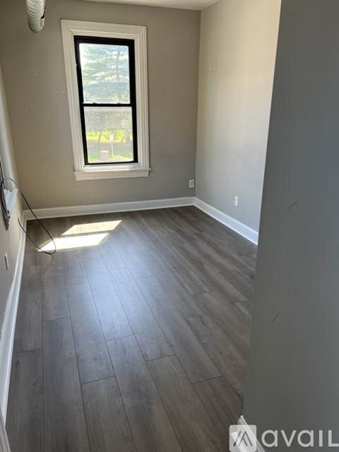 A room with a window and wooden flooring.