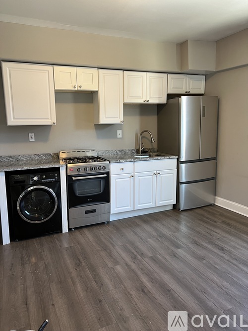 A kitchen with white cabinets and a stainless steel refrigerator.