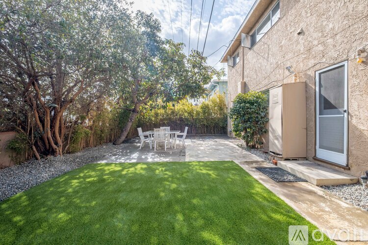 A backyard with a lawn, trees, and a patio table.
