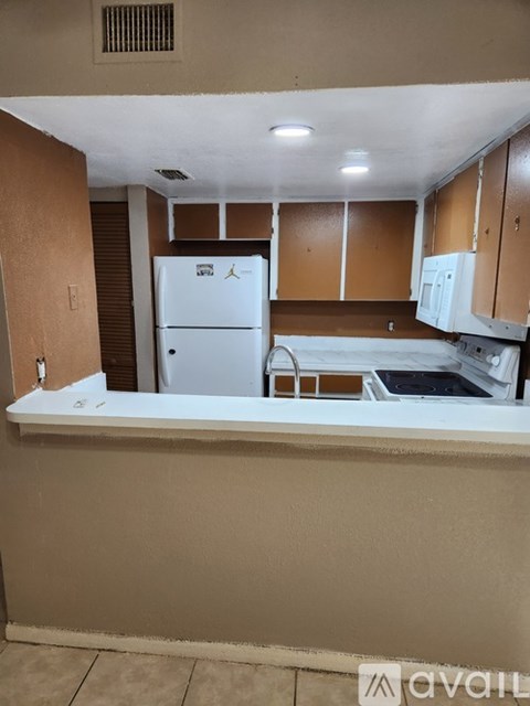 A kitchen with white appliances and brown cabinets.