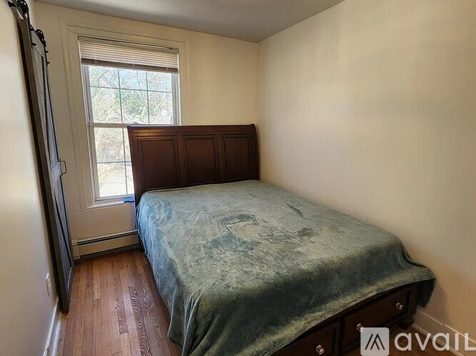 A bedroom with a bed, wooden floors, and a window.