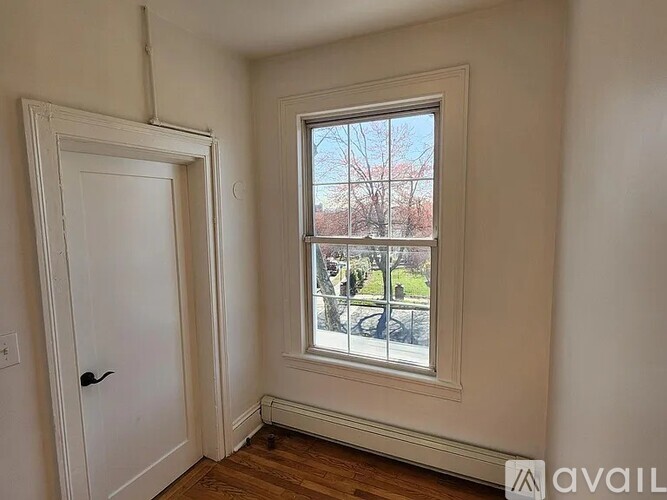 A room with a door and a window showing a view of a tree and a building outside.