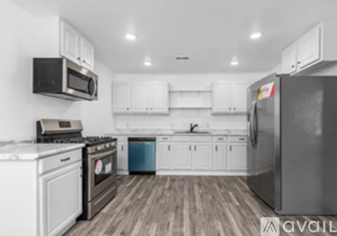 A kitchen with white cabinets and a black fridge.