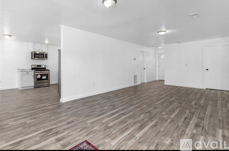 A spacious room with wooden flooring and white walls.