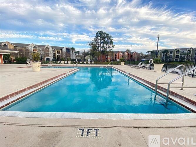 A large swimming pool with a blue tinted water and a white tiled edge.