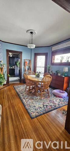 A living room with a wooden floor and a dining table with chairs.