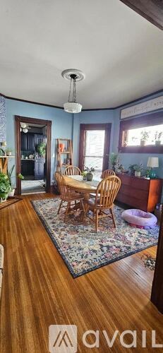 A living room with a wooden floor and a dining table with chairs.