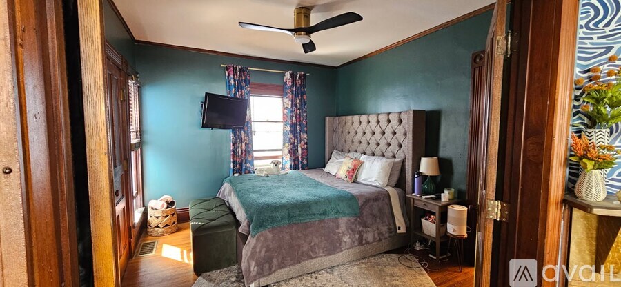 A bedroom with a bed, a ceiling fan, and a window with curtains.