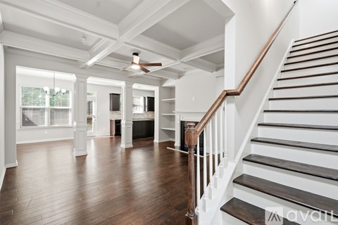 A spacious room with wooden floors and a staircase leading to the upper level.