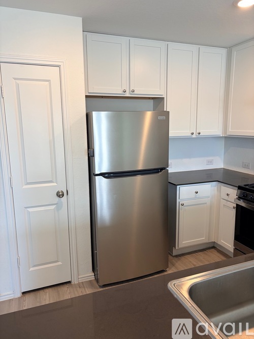 A kitchen with a stainless steel refrigerator and white cabinets.