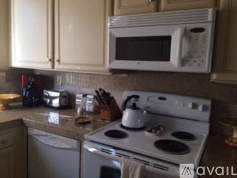 A white microwave oven is mounted above a white gas stove in a kitchen.