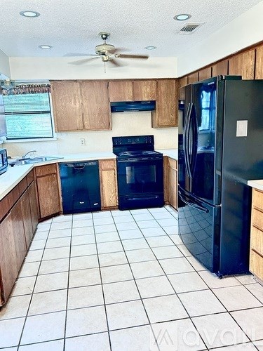 A kitchen with black appliances and wooden cabinets.