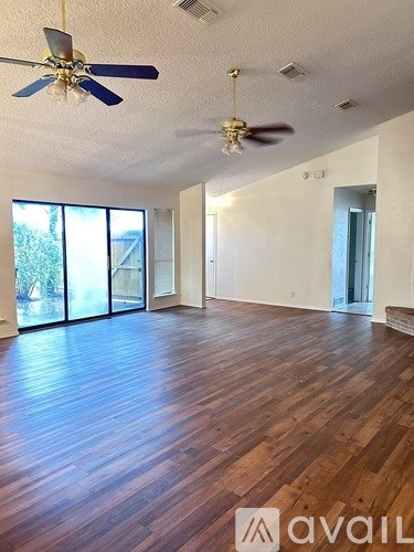 A room with wooden floors and two ceiling fans.