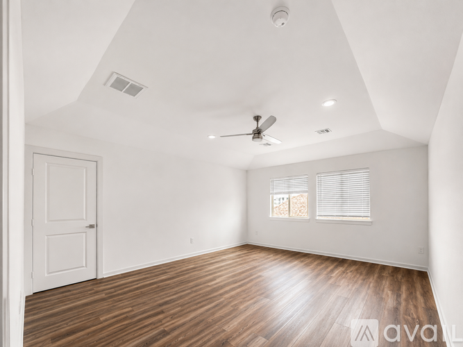 A spacious room with wooden flooring and a ceiling fan.