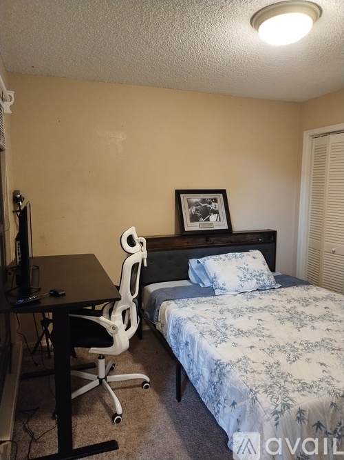A bedroom with a bed, a desk with a computer, and a chair.
