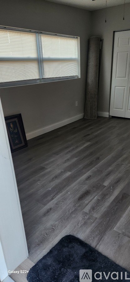 A room with wooden flooring and a window with blinds.