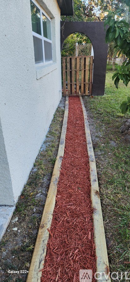 A red brick pathway leads to a wooden gate.