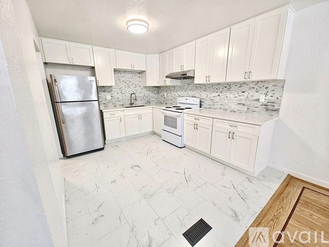A kitchen with white cabinets and marble countertops.
