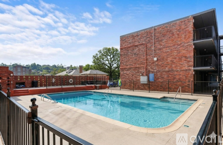 A pool is surrounded by a brick wall and a metal fence.