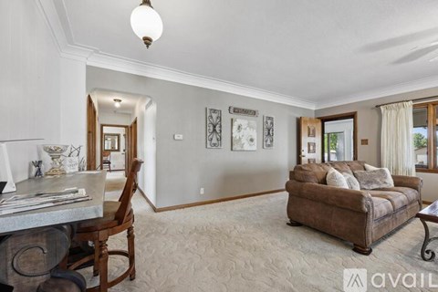 A living room with a brown couch and a dining table with chairs.