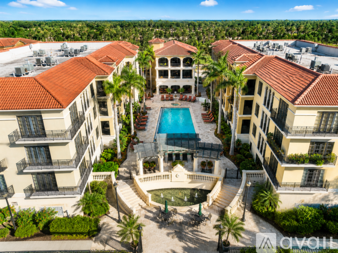 A large building with a pool in the middle of a courtyard surrounded by palm trees.