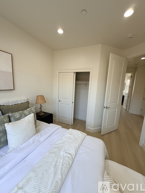 A bedroom with a large bed and a lamp on a side table.