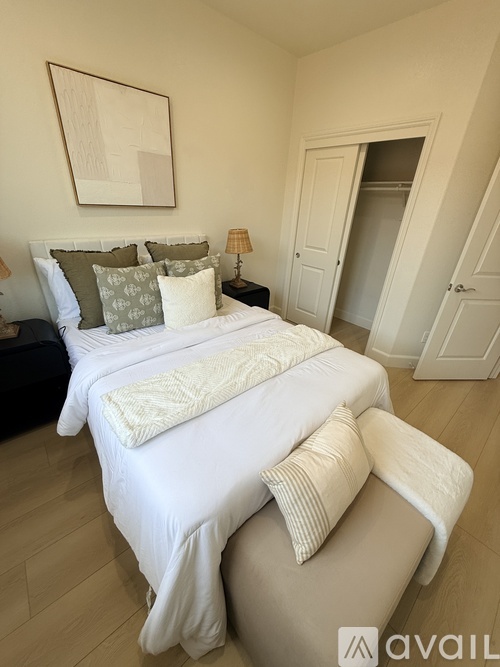 A bedroom with a large bed and a painting on the wall.