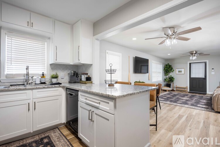 A kitchen with white cabinets and a marble countertop.
