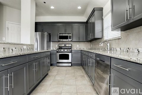 A modern kitchen with dark grey cabinets and stainless steel appliances.