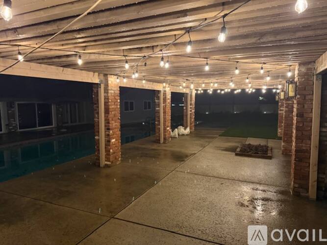 A spacious indoor area with brick columns and string lights on the ceiling.