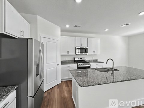 A modern kitchen with white cabinets and a black refrigerator.