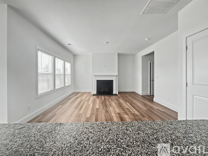 A spacious living room with a fireplace and hardwood floors.