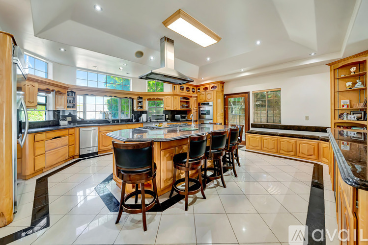 A kitchen with wooden cabinets and a large island with chairs.