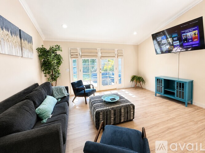 A living room with a couch, chair, ottoman, and a television.