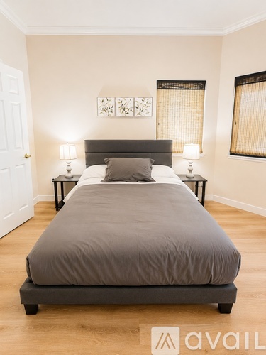 A bedroom with a large bed and two lamps.