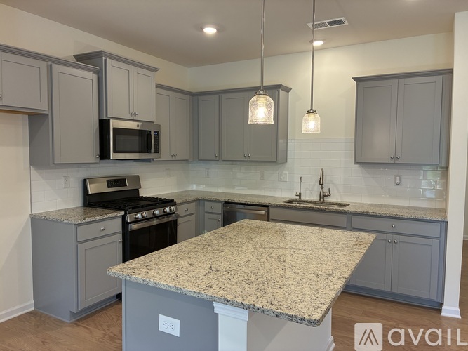 A kitchen with granite countertops and grey cabinets.