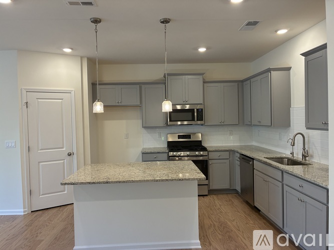 A kitchen with a granite countertop and grey cabinets.