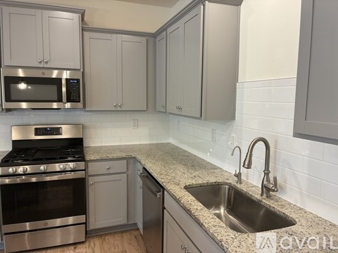 A kitchen with a stove, oven, sink and cabinets.