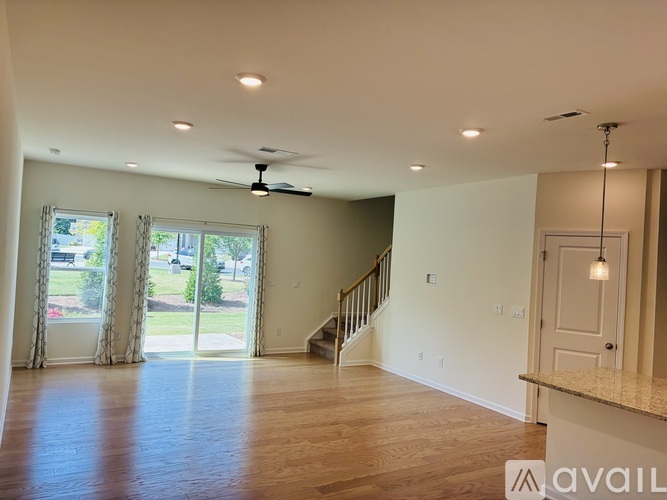 A spacious room with a staircase and a ceiling fan.