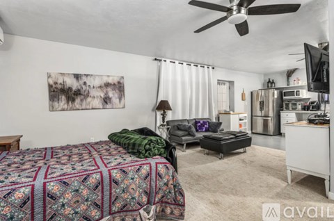 A bedroom with a patterned bedspread and a ceiling fan.