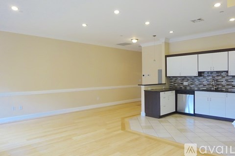 A kitchen area with wooden floors and a stone backsplash.