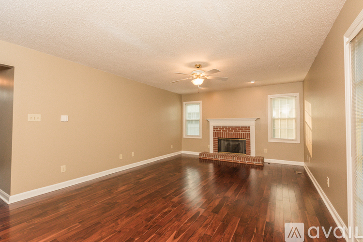 A spacious living room with wood flooring and a fireplace.