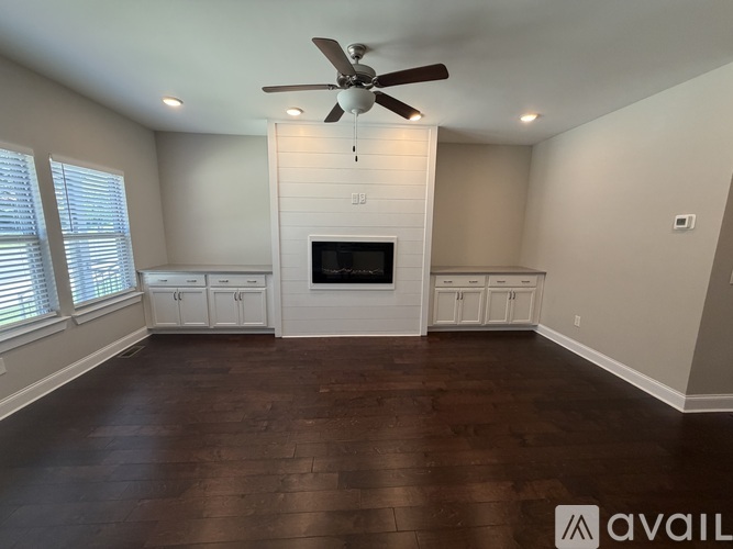 A spacious living room with a fireplace and a ceiling fan.
