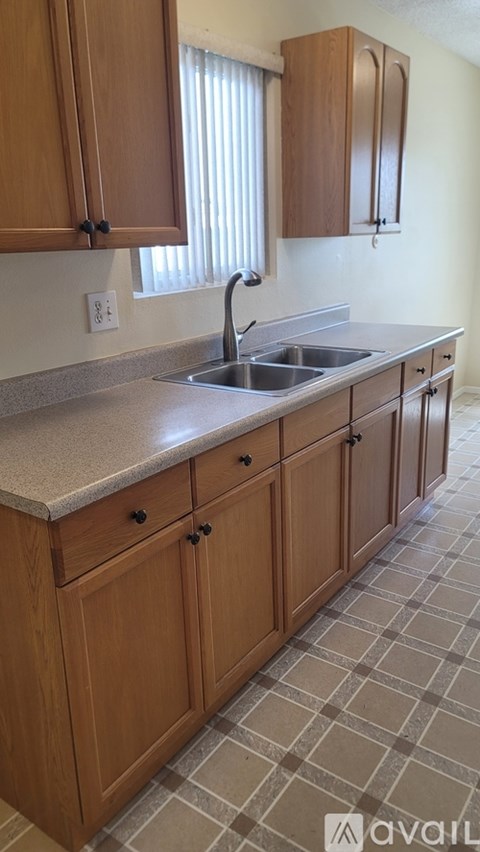 A kitchen with wooden cabinets and a checkered floor.