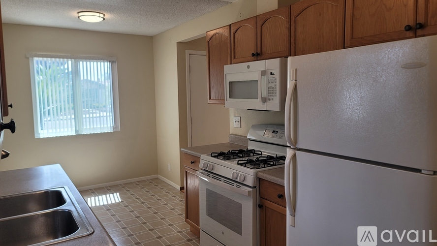 A kitchen with a white refrigerator, stove, and sink.