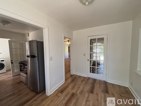 A kitchen with a stainless steel refrigerator and wooden floors.