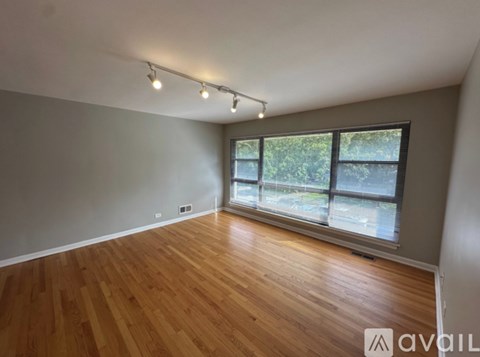 A room with wooden flooring and a large window.