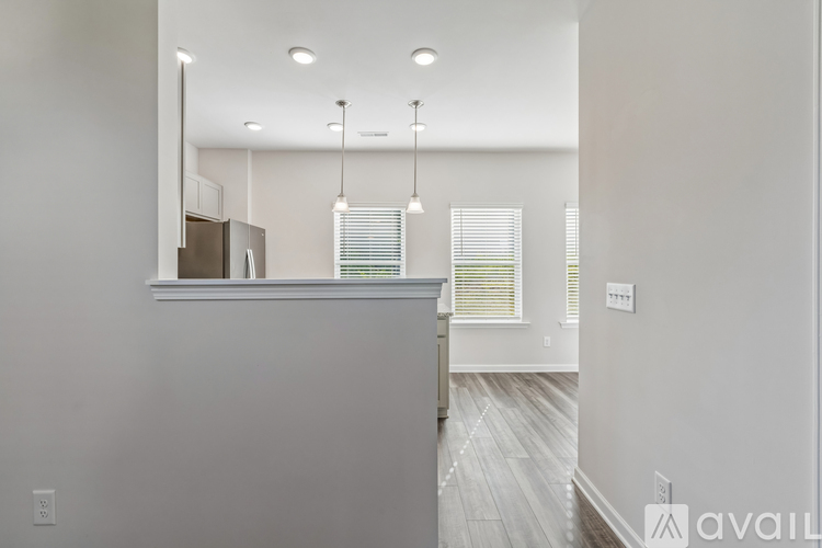 A modern kitchen with a stainless steel refrigerator and wooden flooring.