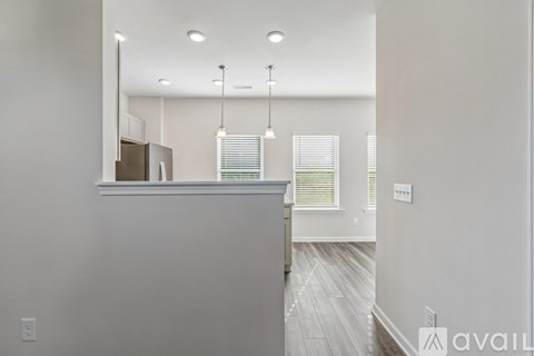 A modern kitchen with a stainless steel refrigerator and wooden flooring.
