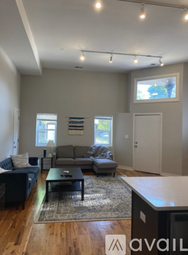 A living room with a black couch, a grey couch, a coffee table, and a rug.
